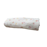 Baby NaturHere maxi muslin tetra pelena with a delicate floral print in pink and yellow on a white background. Made of 100% cotton.