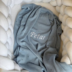 Gray baby blanket with 'Petar' embroidery on a white textured surface