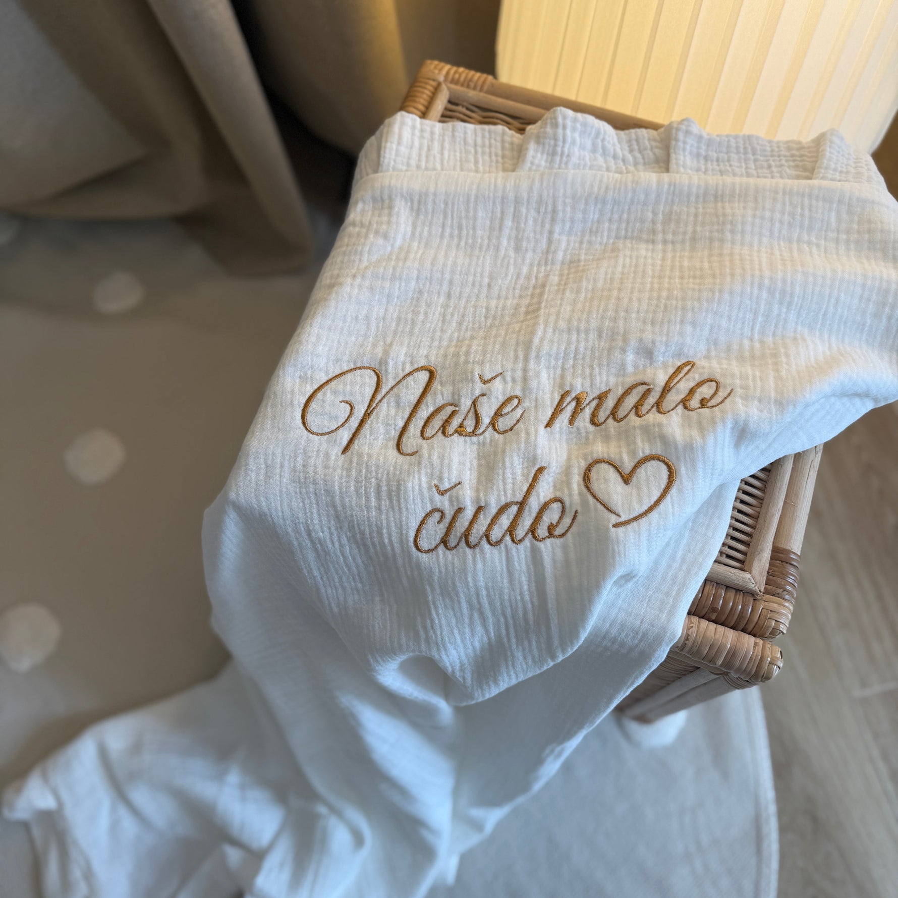 White baby outfit with embroidered text on a polka dot surface