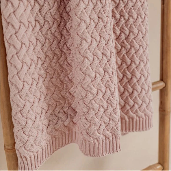 Pink textured sweater draped over a wooden rack.