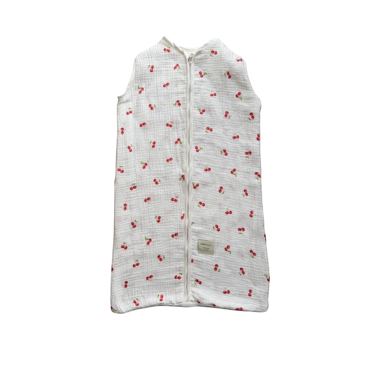 Baby Natur sleeveless sleeping bag with a white background and a red cherry print. Made from soft, breathable cotton.