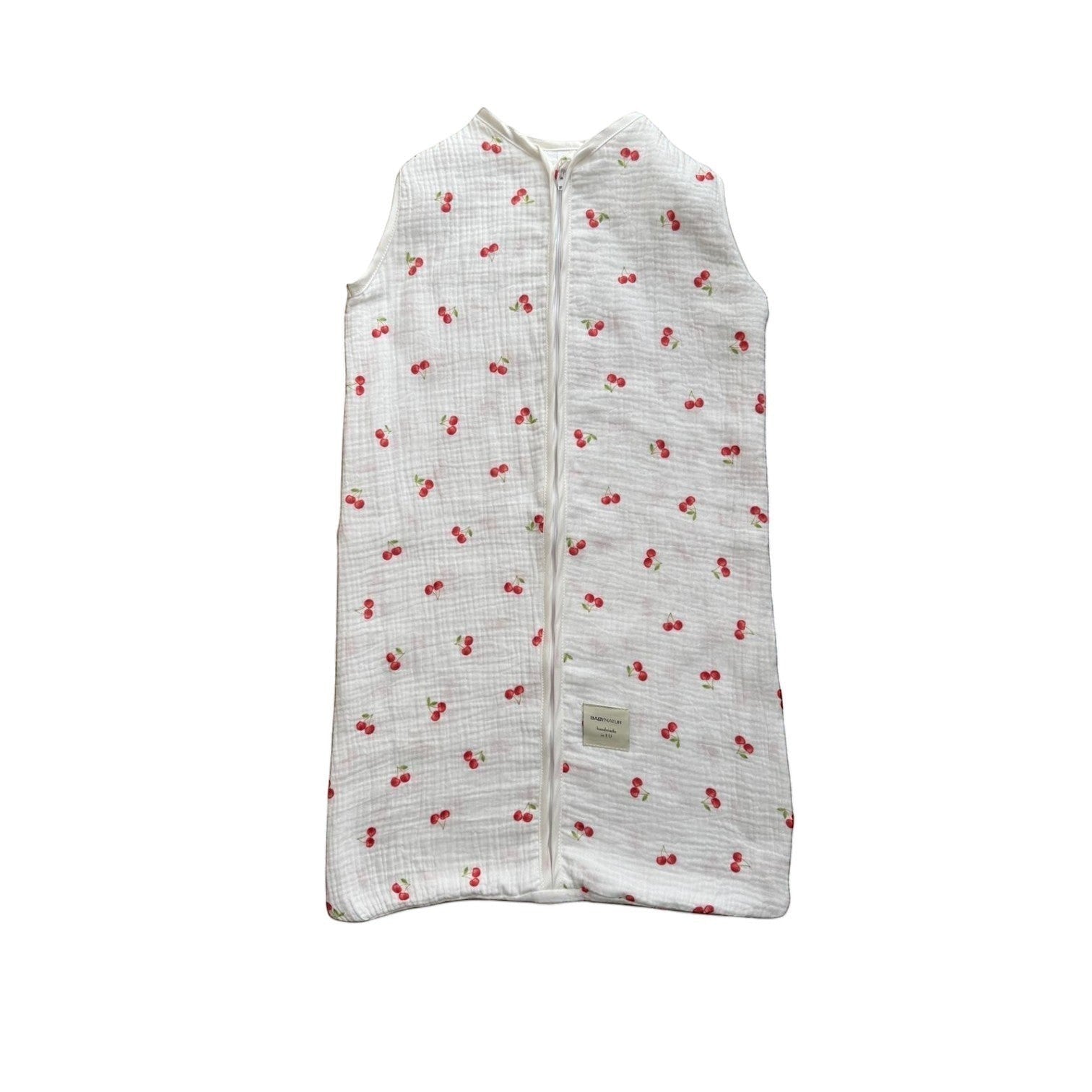 Baby Natur sleeveless sleeping bag with a white background and a red cherry print. Made from soft, breathable cotton.