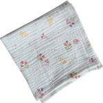 Baby Natur white cotton muslin swaddle blanket with a delicate floral print of pink and purple flowers and yellow accents.