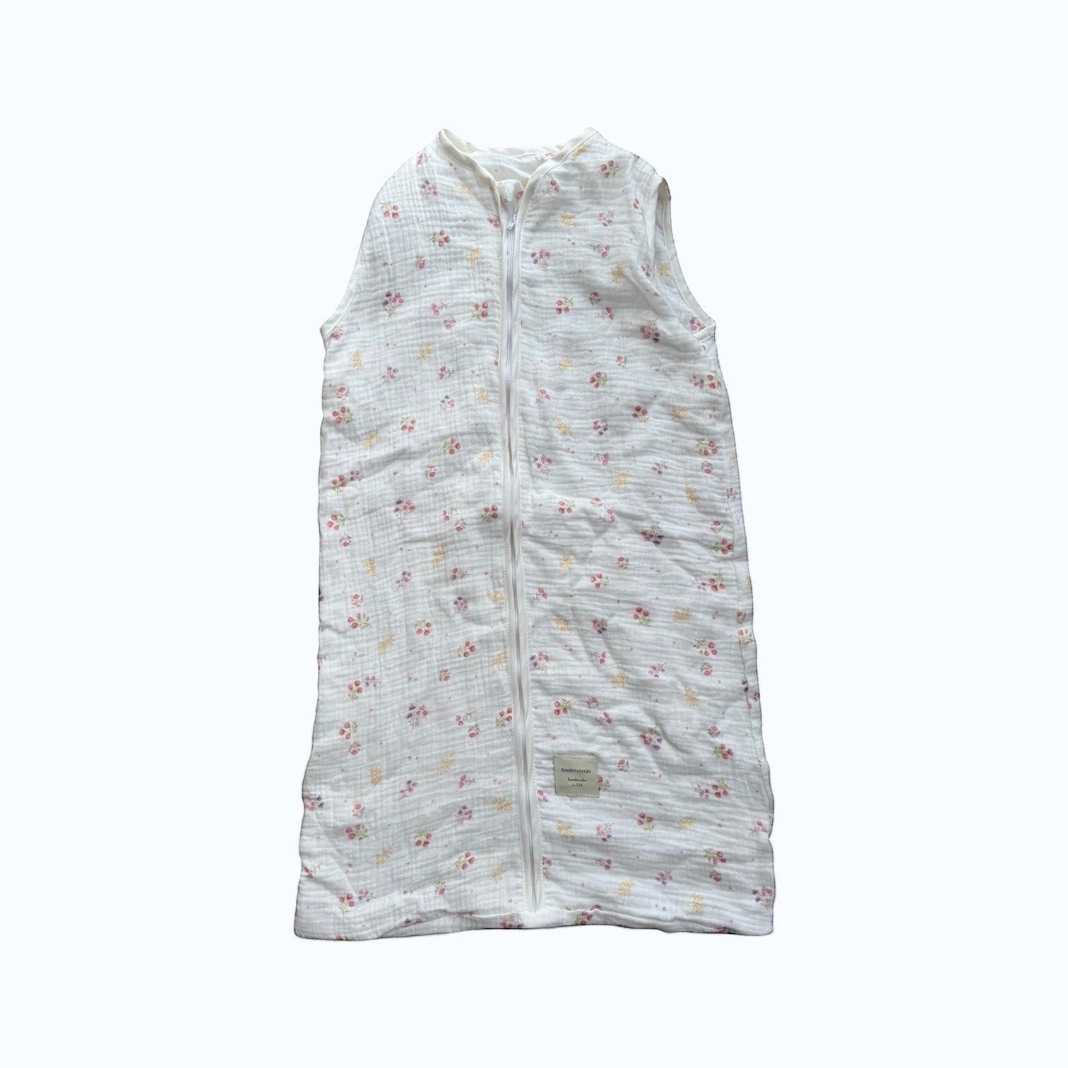 Baby Natur sleeveless sleeping bag with a white background and a delicate floral print in pink and yellow. Made from soft, breathable cotton.