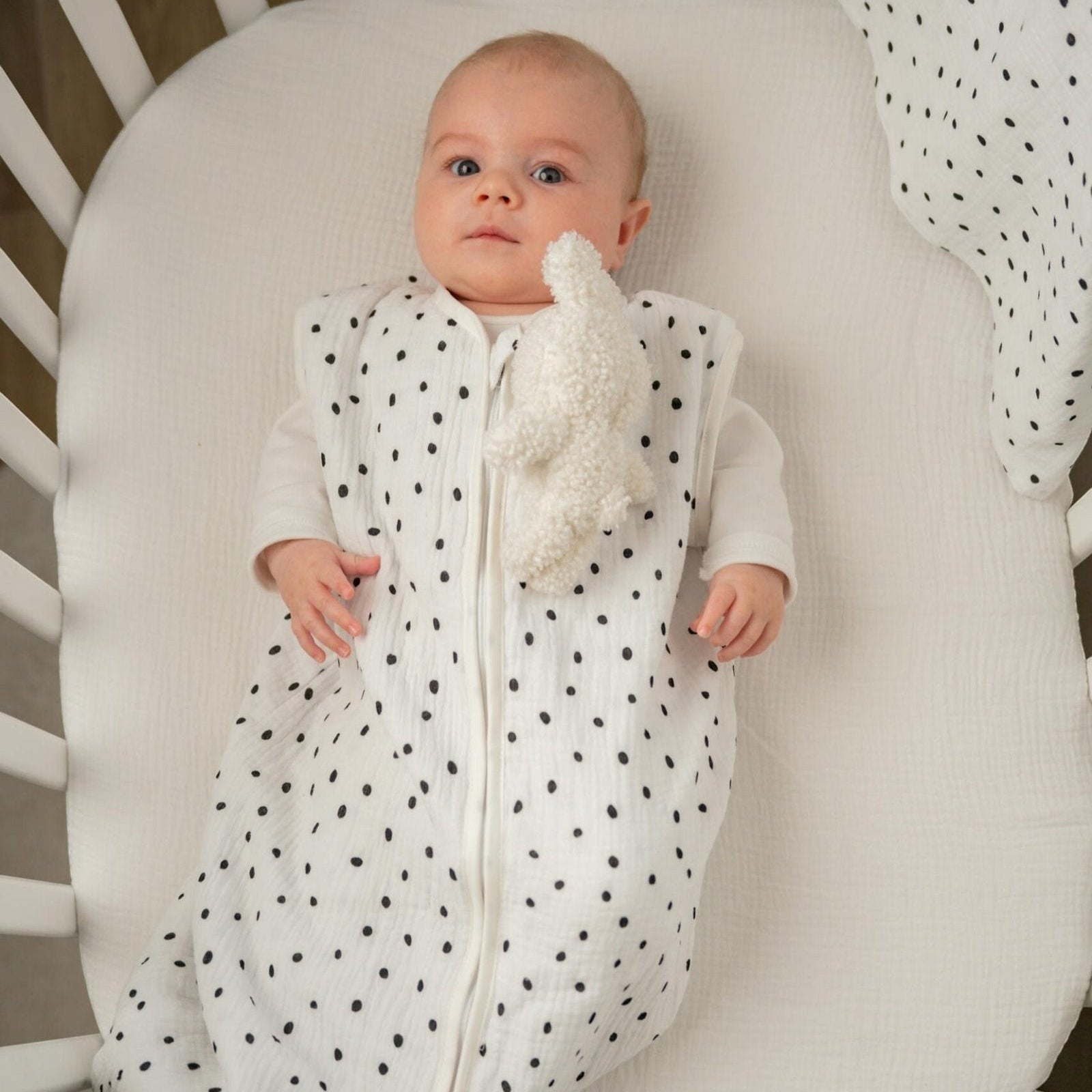 Baby Natur white sleeveless sleeping bag with black polka dots, made of soft, breathable cotton. Features a zipper closure.