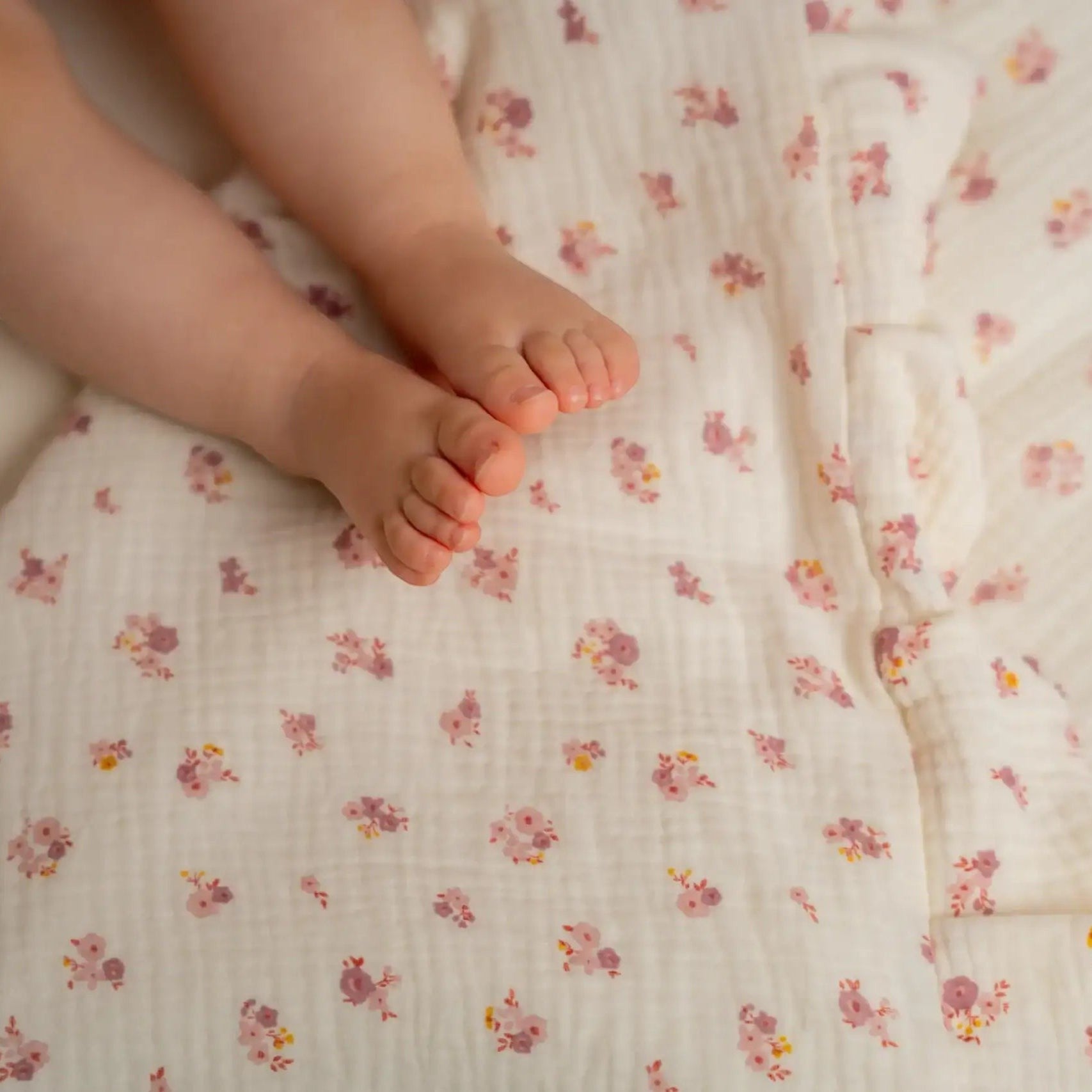 Baby Natur Tetra muslin bedding with a delicate floral print in pink and yellow on a cream background. Features ruffled edges and is made from 100% organic cotton.