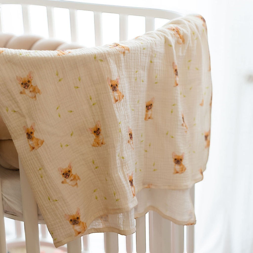 Baby NaturA cream 100% cotton muslin swaddle blanket with a French bulldog and leaf print.