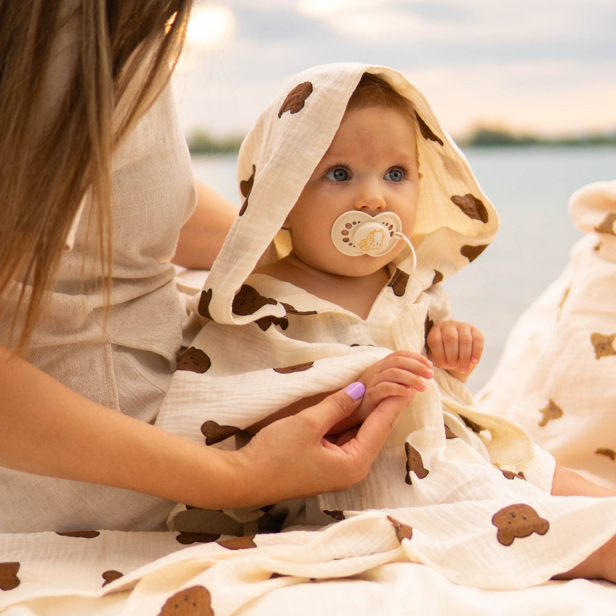Baby Natur cream muslin hooded poncho with brown bear print, featuring a pacifier.