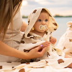 Baby Natur cream muslin hooded poncho with brown bear print, featuring a pacifier.