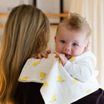 Baby NaturStandard tetra diaper made of 100% cotton with a lemon print, draped over a woman's shoulder.