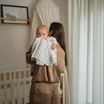 Baby NaturHere standard tetra diaper made of 100% cotton with black polka dots, used by a mother to burp her baby.