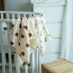 Baby NaturHere 100% cotton muslin swaddle blanket with brown teddy bear print. Soft, absorbent, and washable.