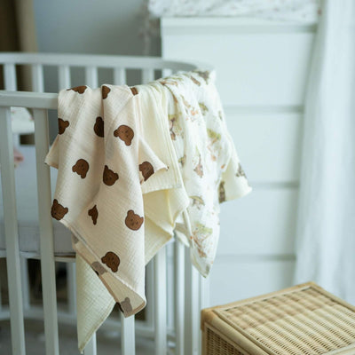 Baby NaturHere 100% cotton muslin swaddle blanket with brown teddy bear print. Soft, absorbent, and washable.