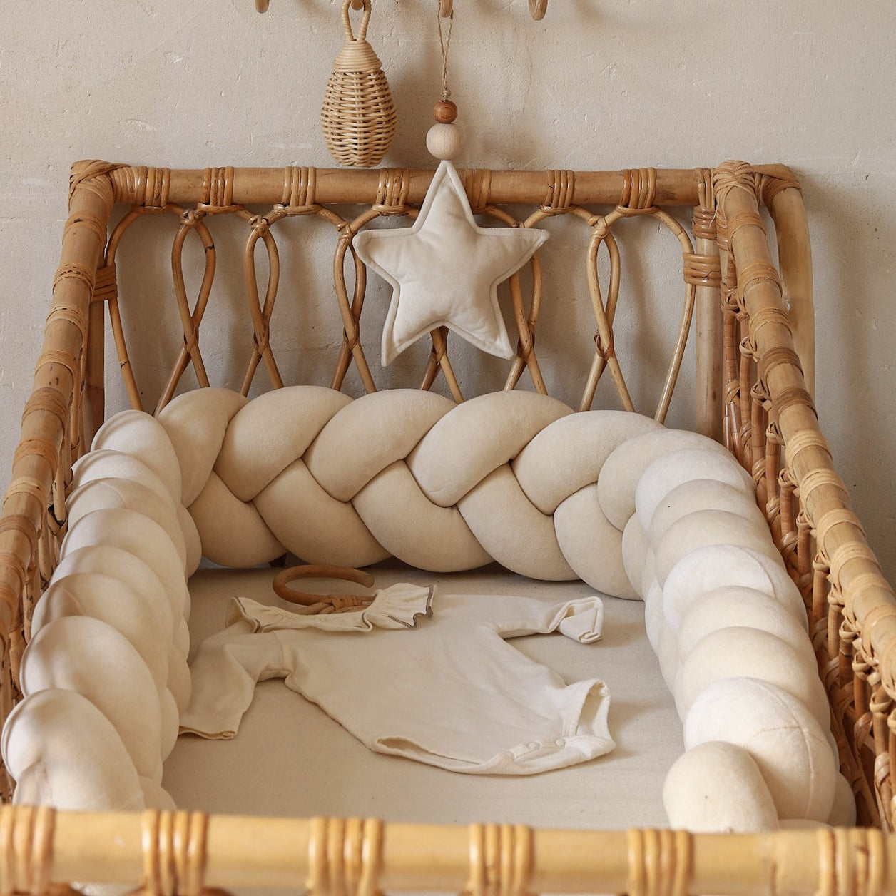 Wicker crib with braided headboard and decorative items against a neutral wall.